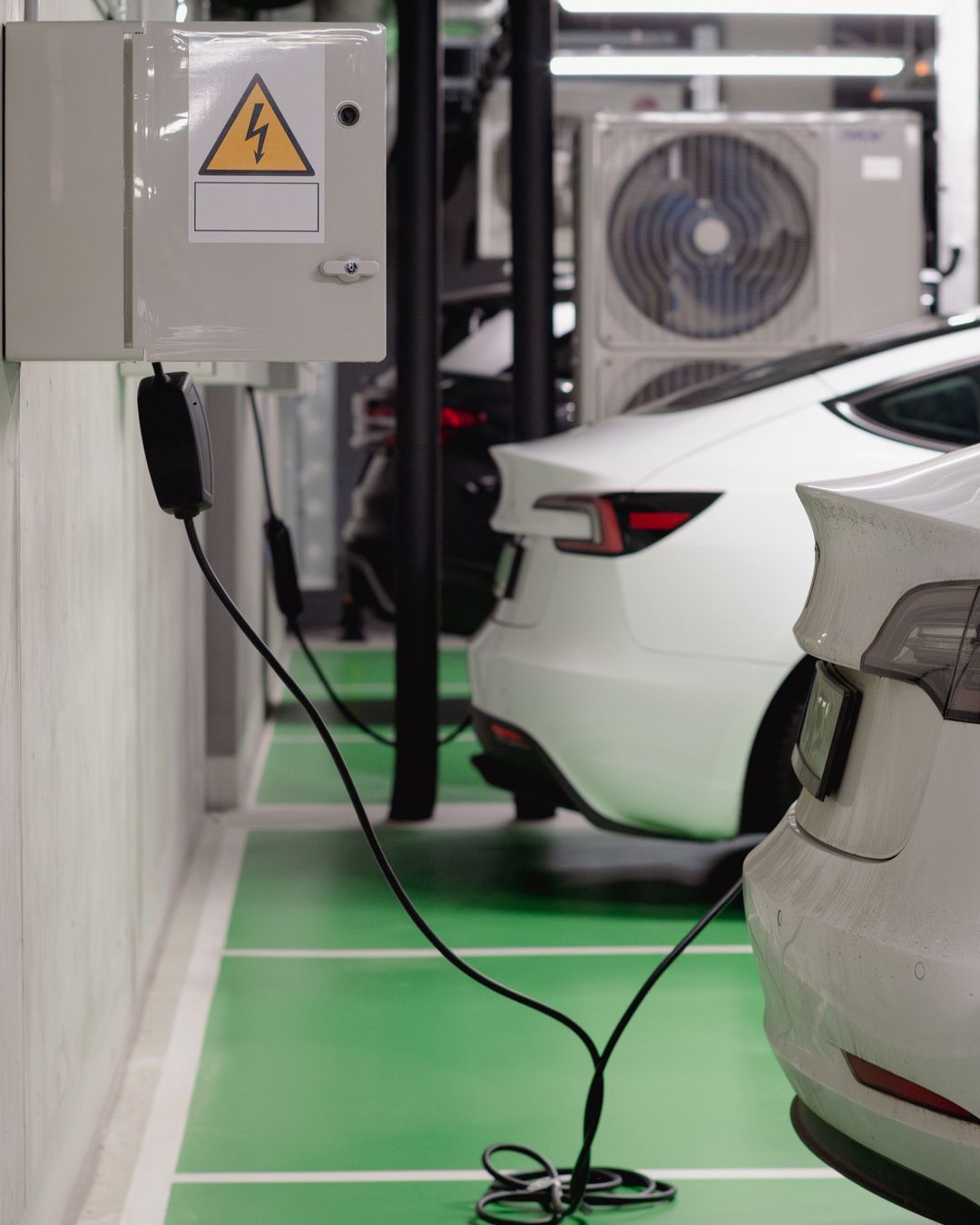 Véhicules électriques en charge dans un parking avec infrastructure électrique visible